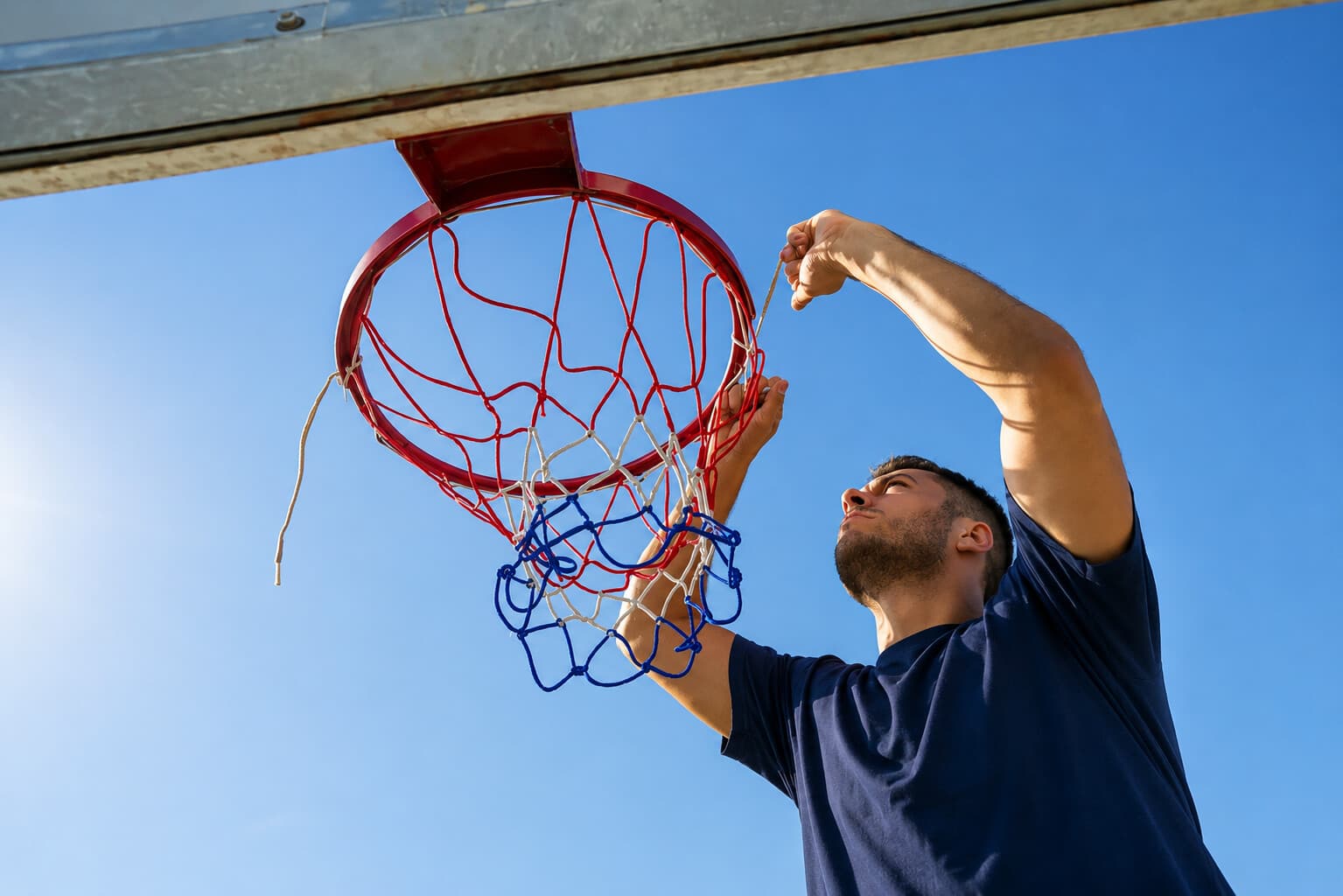 Close-up of a technician tying a new net onto the rim against a clear sky